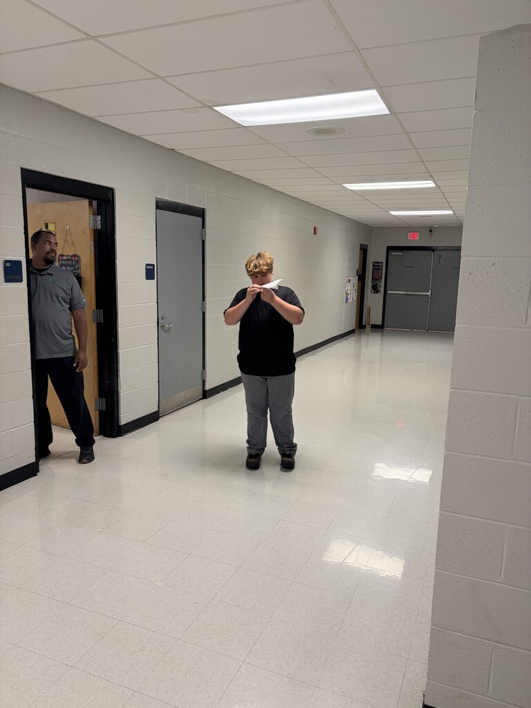 A student making sure his airplane is ready while Mr. Ray watches. 