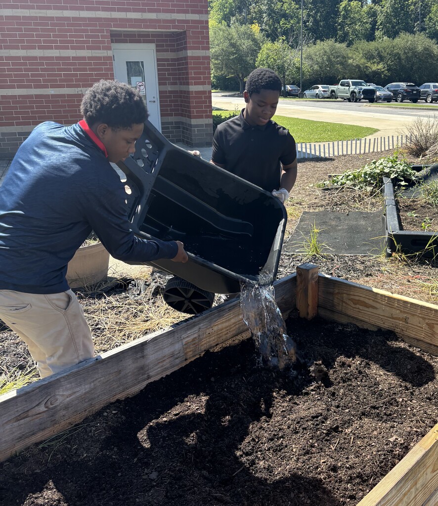 TLC students wetting down the soil in the raised garden beds