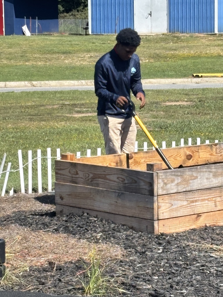 TLC student shoveling the soil in the raised garden bed.