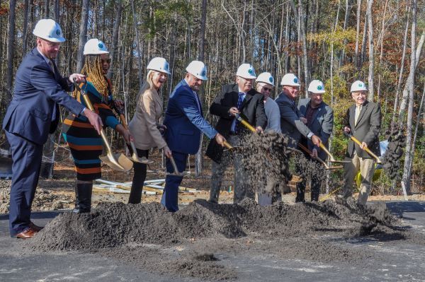 Officials in hard hats throwing dirt from shovels