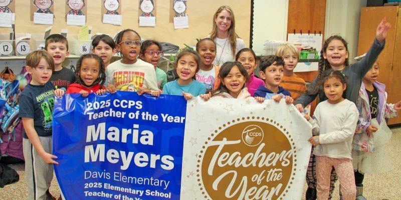 A group of students holding a banner announcing Maria Meyers as Teacher of the Year