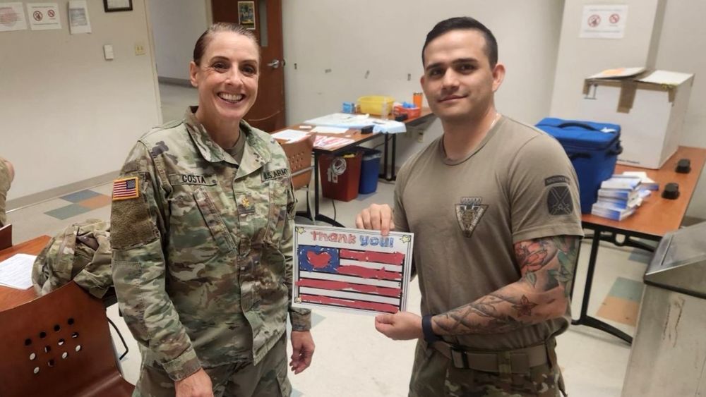 Two military personnel holding a hand-drawn flag