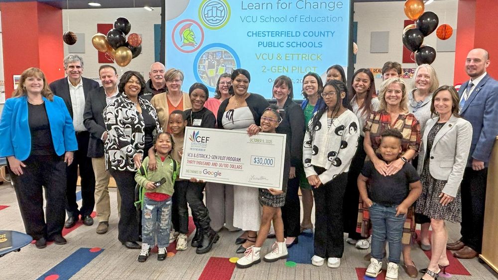 Group standing with large check