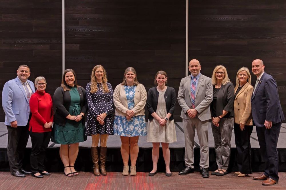 School board members standing with newly certified teachers