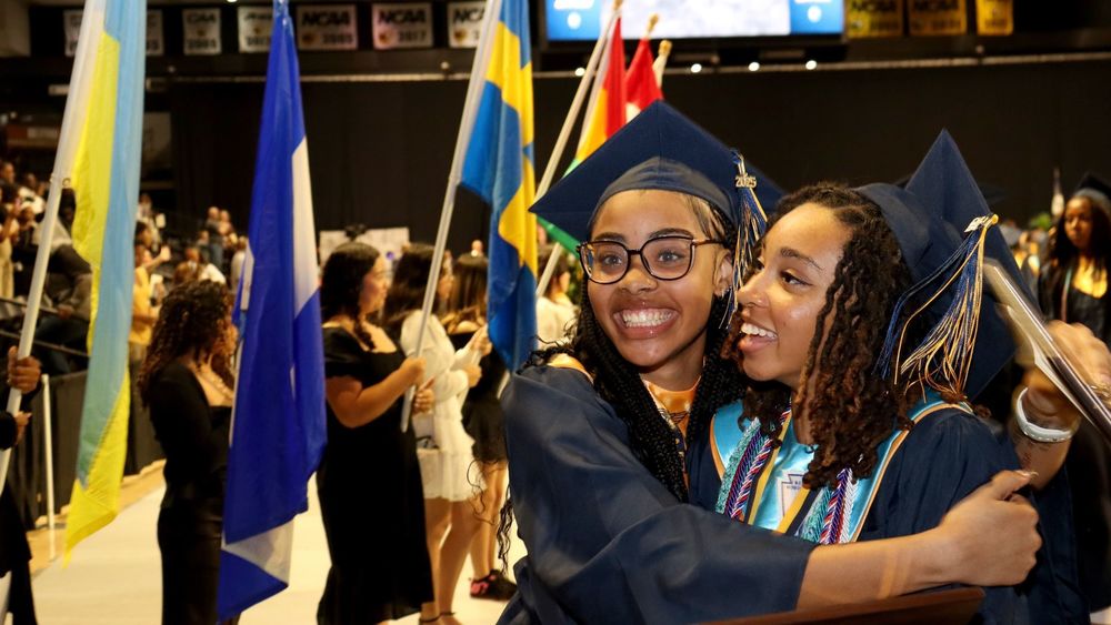 Two grads smiling and hugging