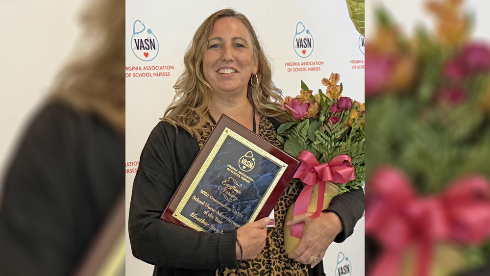 Heather Snyder holding a plaque and flowers
