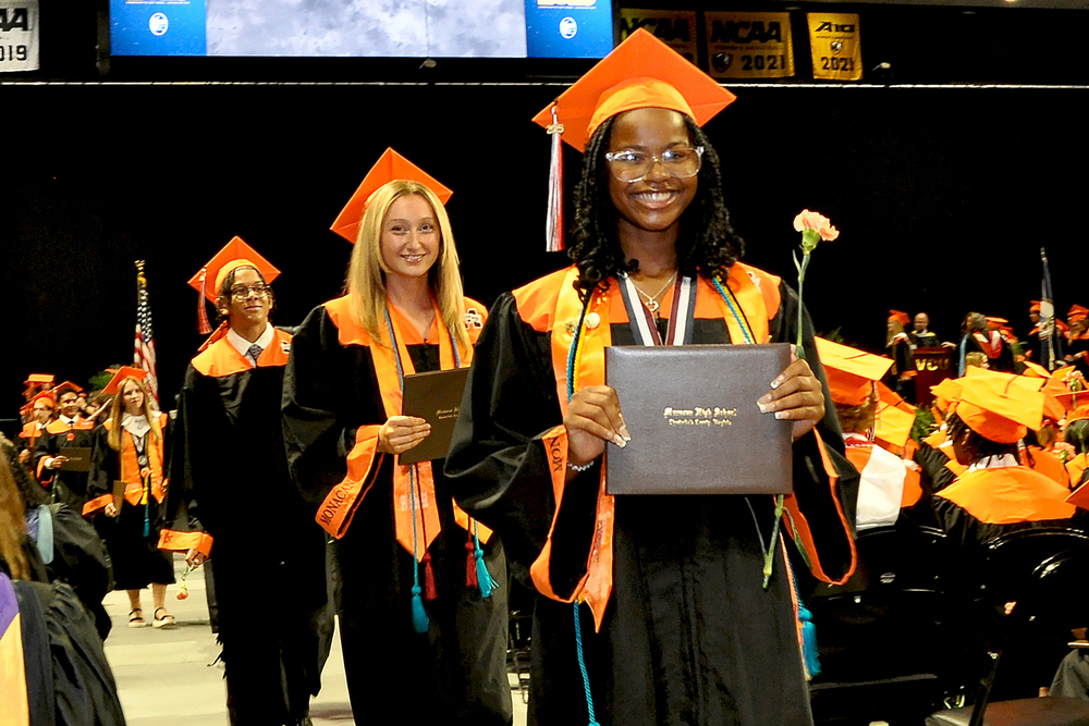 Three graduates holding diplomas