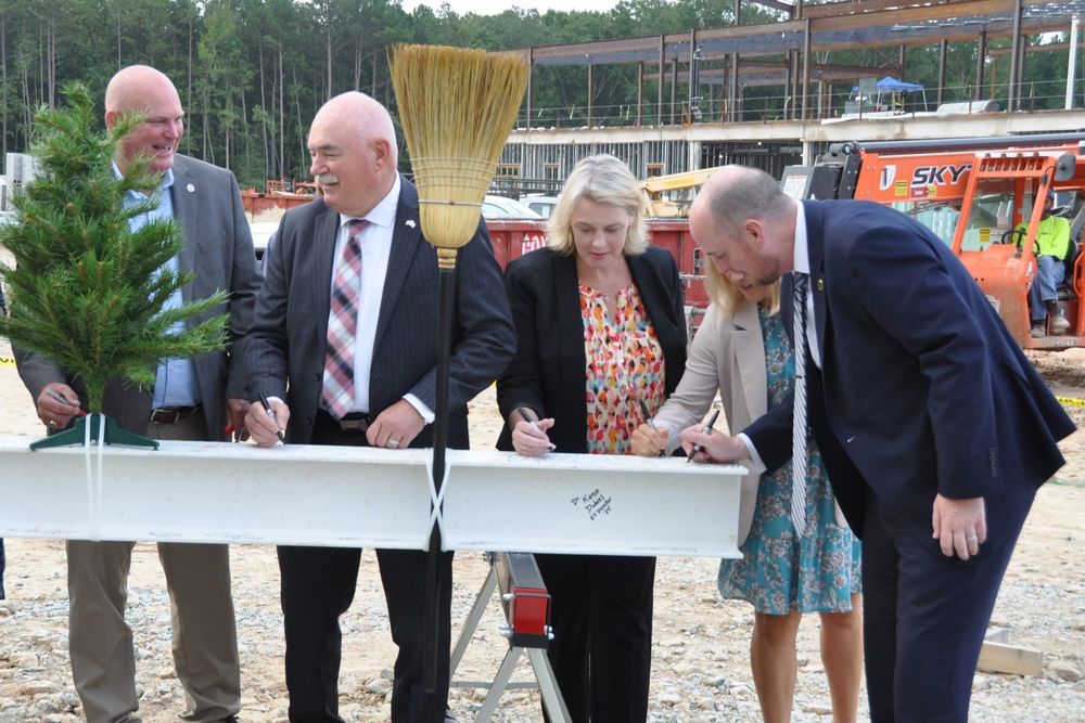 School leaders signing a beam