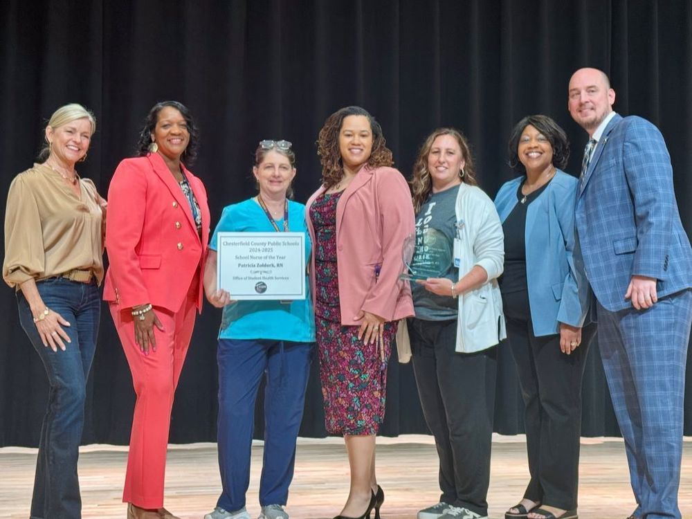 Nurse Z standing with a group, holding her award