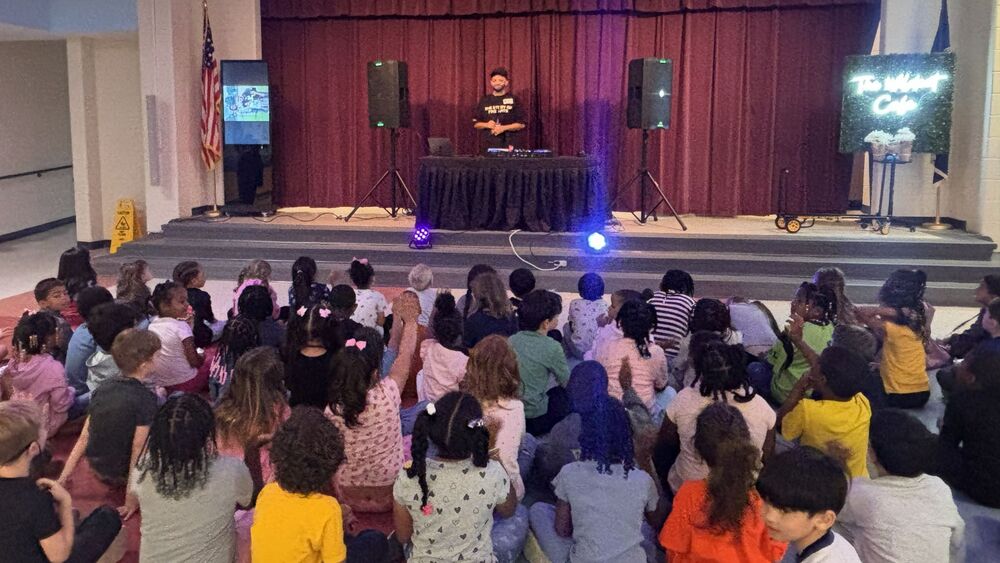 A DJ in front of a large group of young students