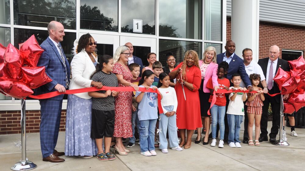 School leaders and county officials cutting a red ribbon