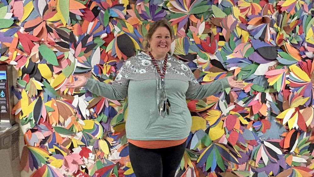 Kelley Perrotte in front of a wall with colorful turkey feathers