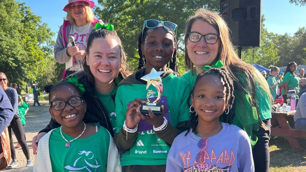 Students smiling and holding a star-shaped trophy