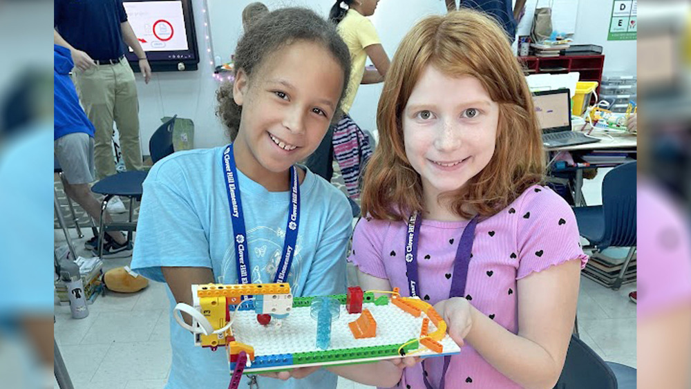 Two young girls holding a lego creation