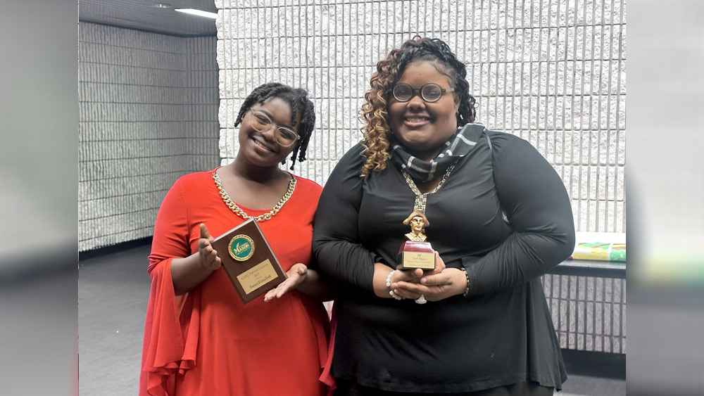 Two students holding awards