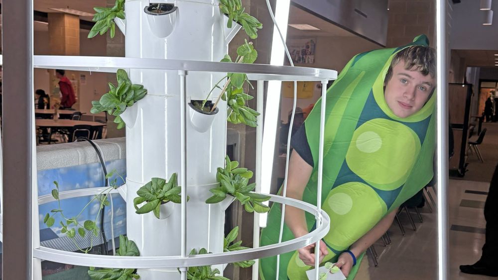 Student in a bean costume next to plants