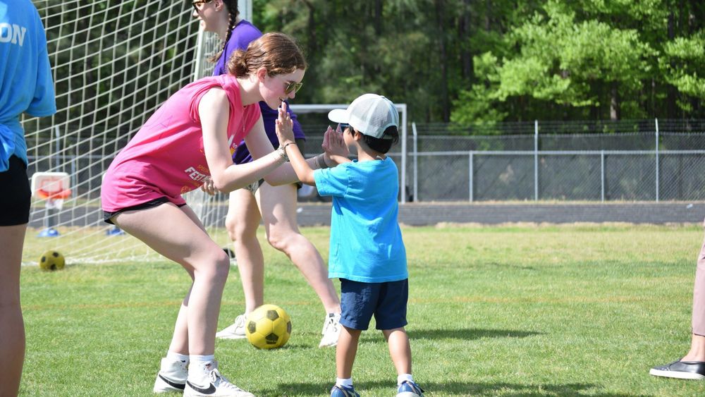 Girl double-high-fiving a young student
