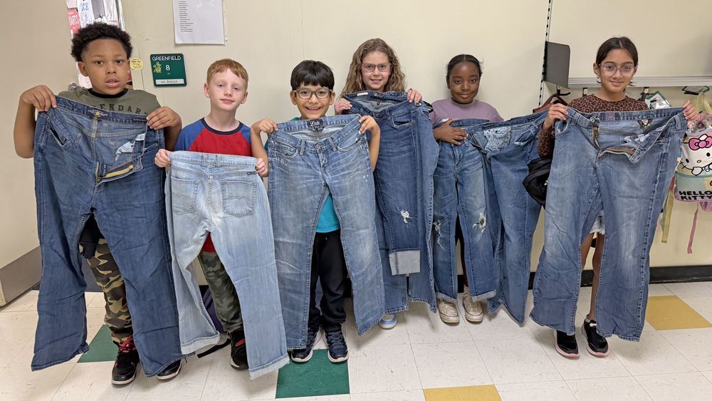 Students holding up pairs of jeans