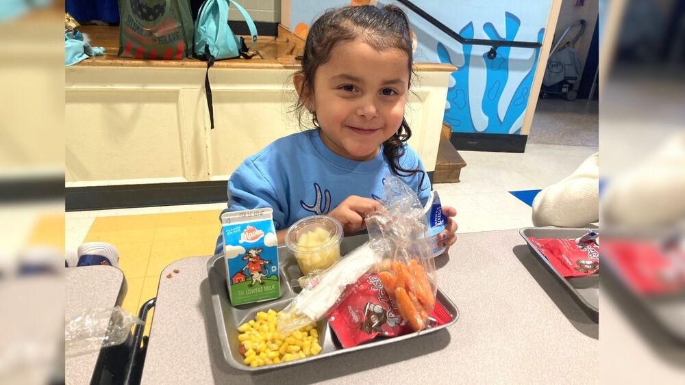 Young girl  smiling with a meal on a cafeteria tray