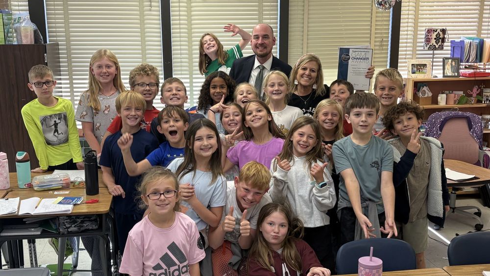 The superintendent and a teacher with a group of smiling students