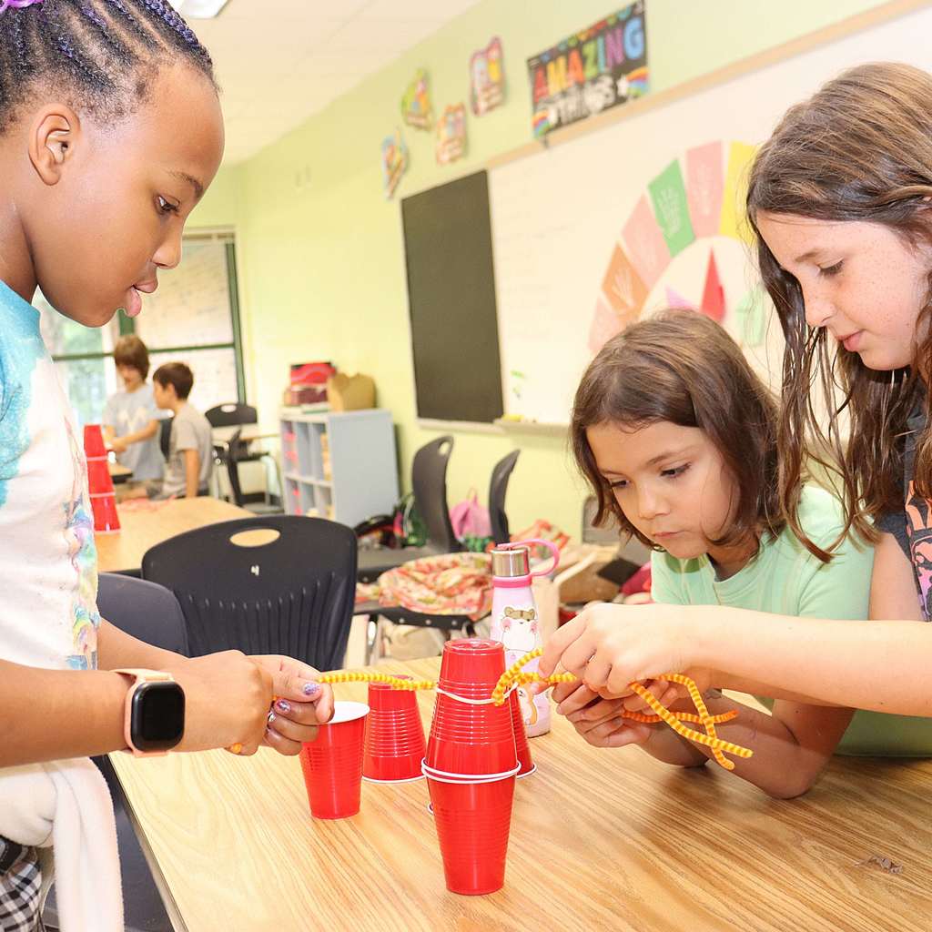 Three students playing a game with red plastic cups