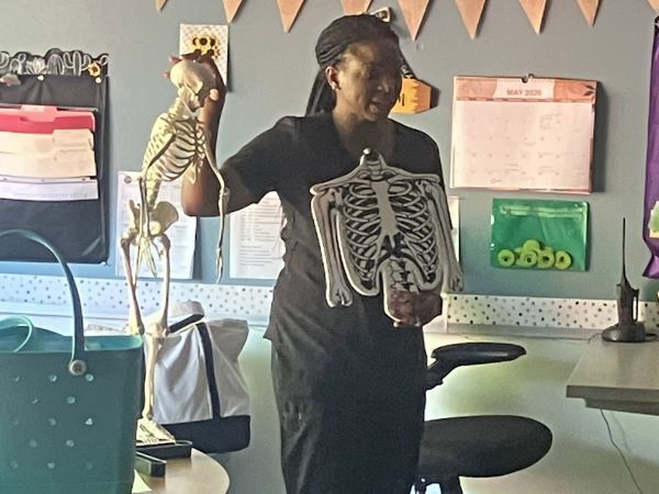 Woman holding up skeleton model