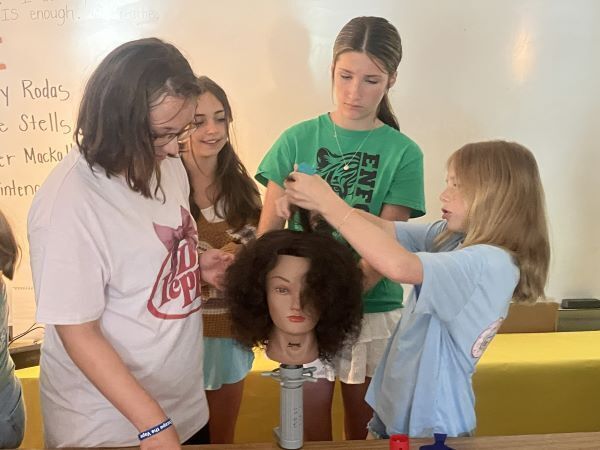 Students cutting hair on a practice head