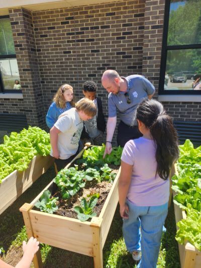 Dr. John Murray looking at plant beds with students