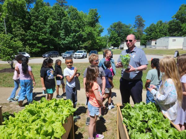 Dr. John Murray holding a green plant and talking to students