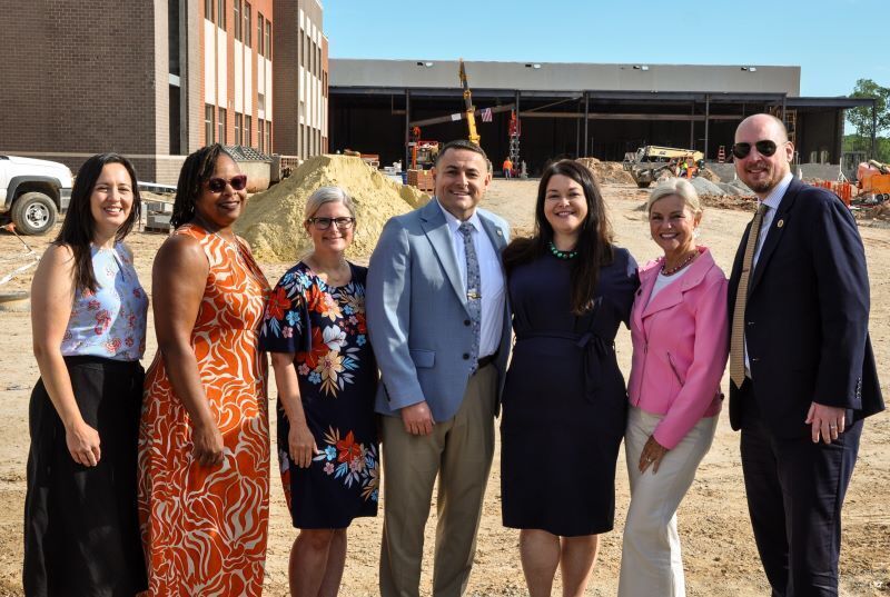 School leaders posing in front of the construction of the new school