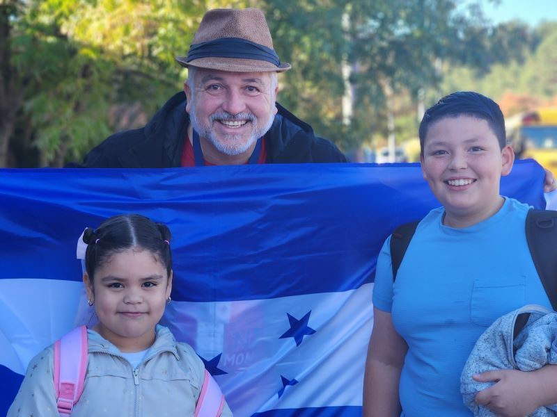 Family smiling while holding flag