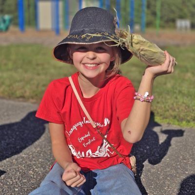 A student holding an ear of corn and smiling