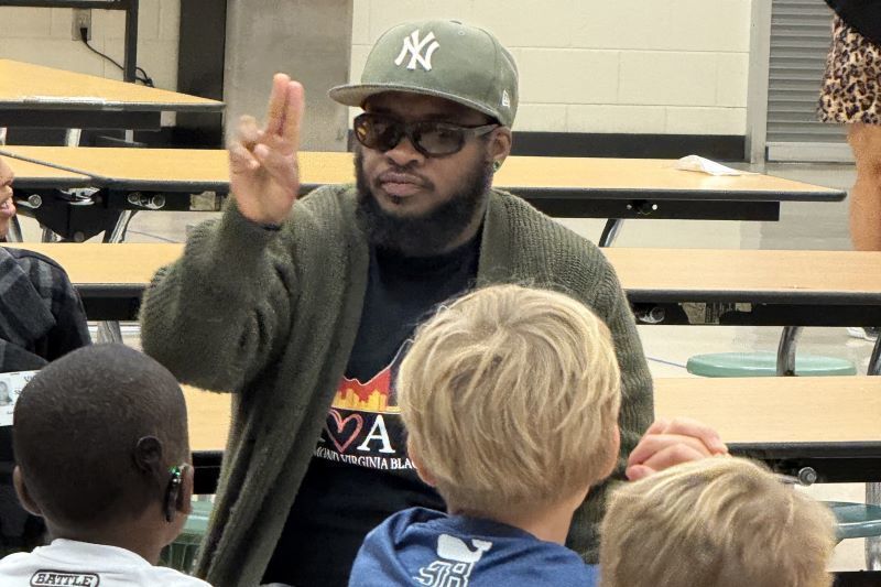 A man in sunglasses showing a  sign