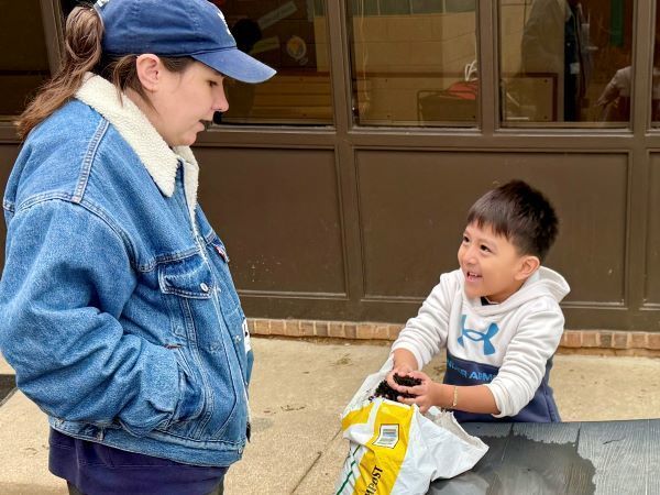 Student smiling with a handful of dirt