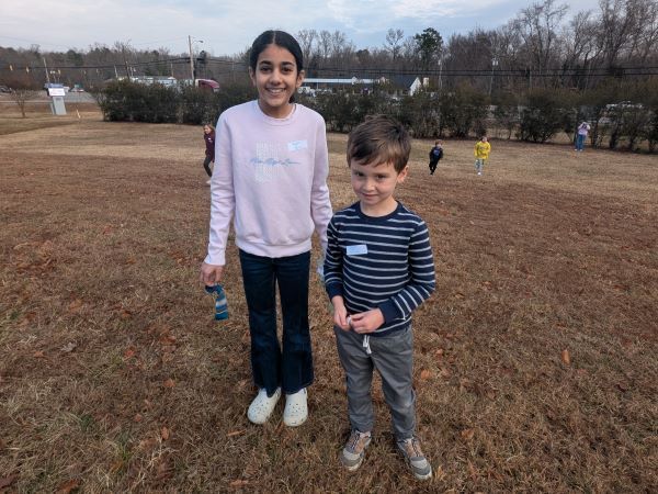 Two students smiling, holding cleaning supplies
