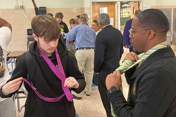 A mentor teaching a student to tie a necktie