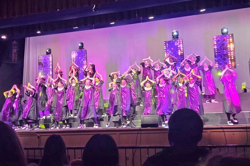 Students in purple outfits dancing