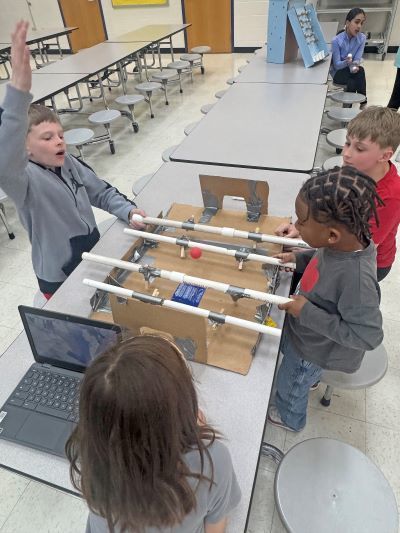 Two students playing a homemade foosball game