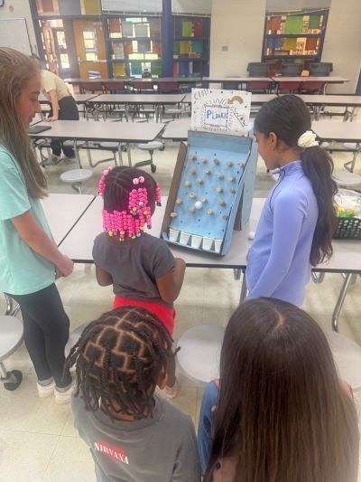 Students playing a homemade plinko game