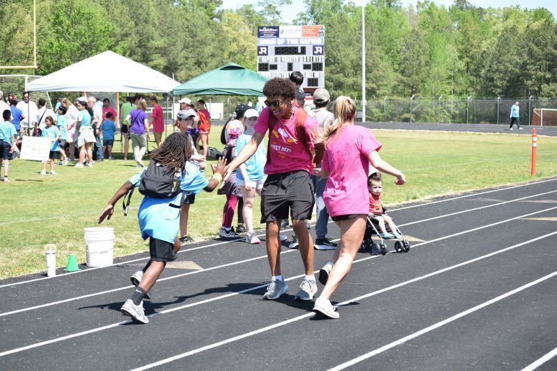 Students running on a track and high-fiving