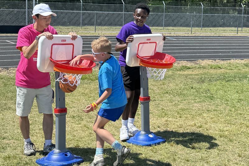 A young student dunking a basketball on a toy hoop