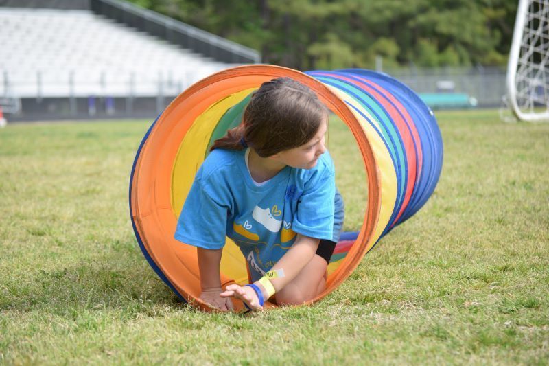 A young student crawling through a colorful tube