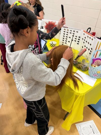 Young student adjusting a wig on a practice head