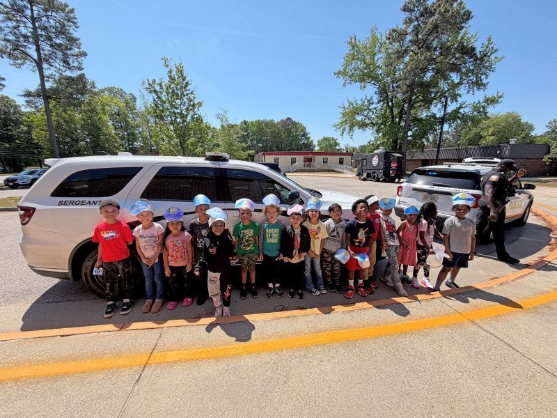 A class of students standing in front of a police cruiser