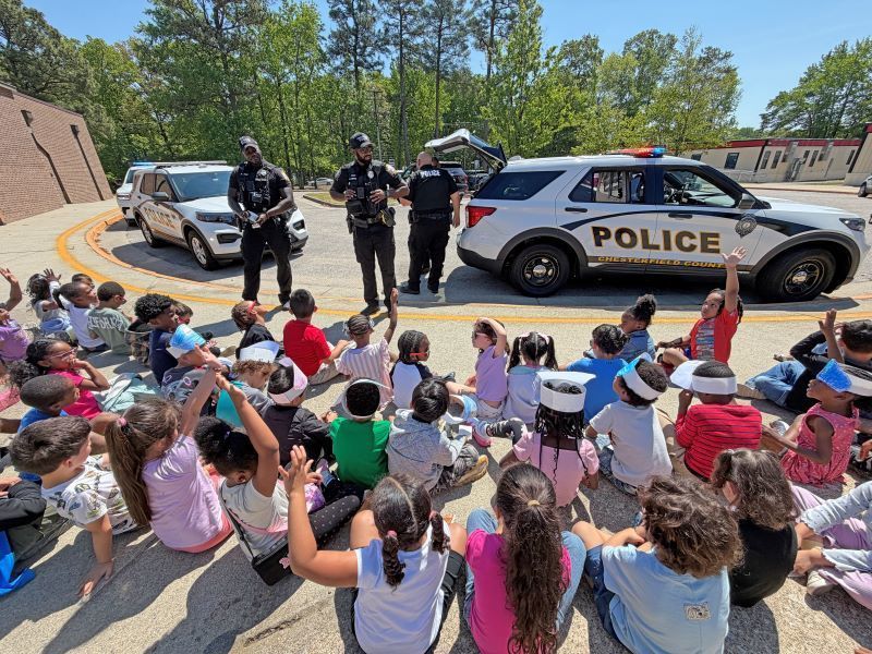 Police officers talking outside in front of seated students