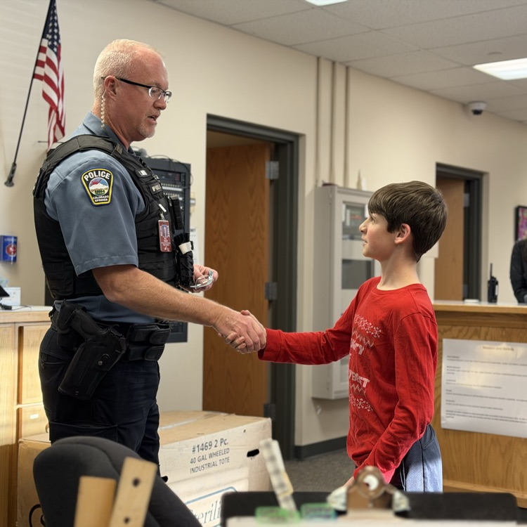 Jaxon Smith being recognized by Officer Bill Walsh  with an SRO Challenge Coin for great things he has done in the community to support families through the government shut down.