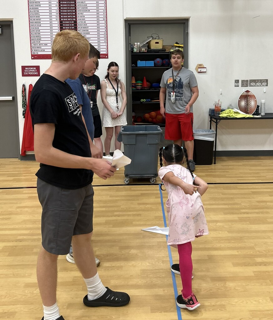 A child throws a paper airplane at the Summer School carnival.