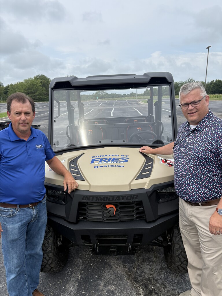 Dr. Dan Wiebers, Superintedent, and a representative of Fries Ag & Turf stand near a side by side UTV.