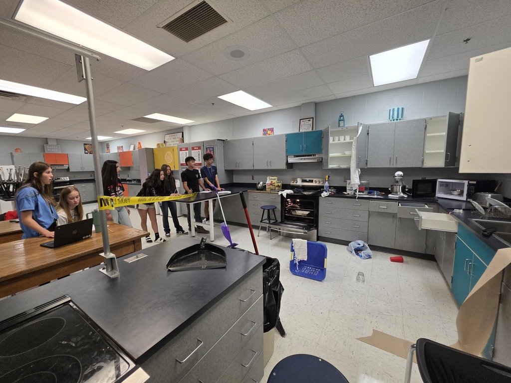 Students in Amanda Hall's Foods class search the room for safety and sanitation hazards behind yellow crime scene tape.