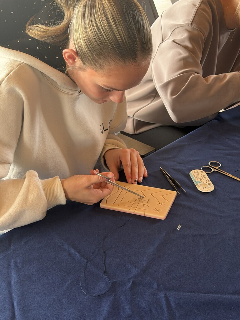A student learns how to cut a suture.